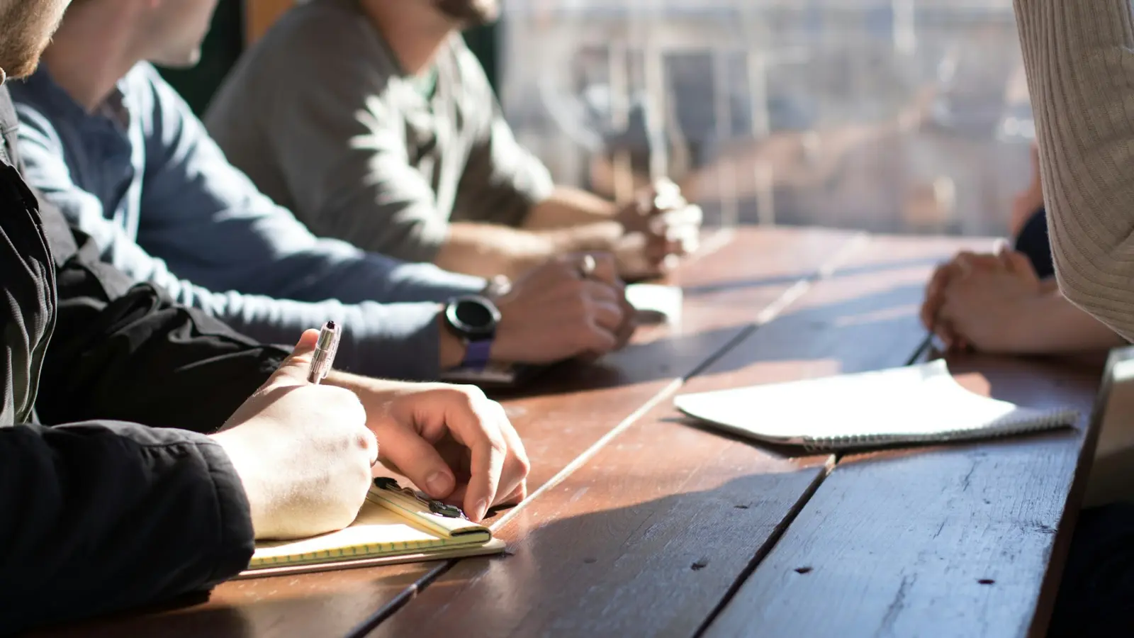 Équipe réunie autour d'une table de travail, carnets ouverts, pendant un atelier